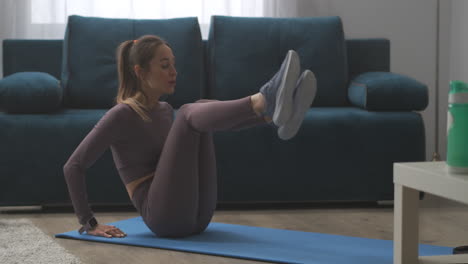 sporty-woman-is-adjusting-fitness-tracker-and-doing-crunches-in-living-room-home-training-of-young-slender-athletic-lady-physical-exercise-for-good-shape-of-body